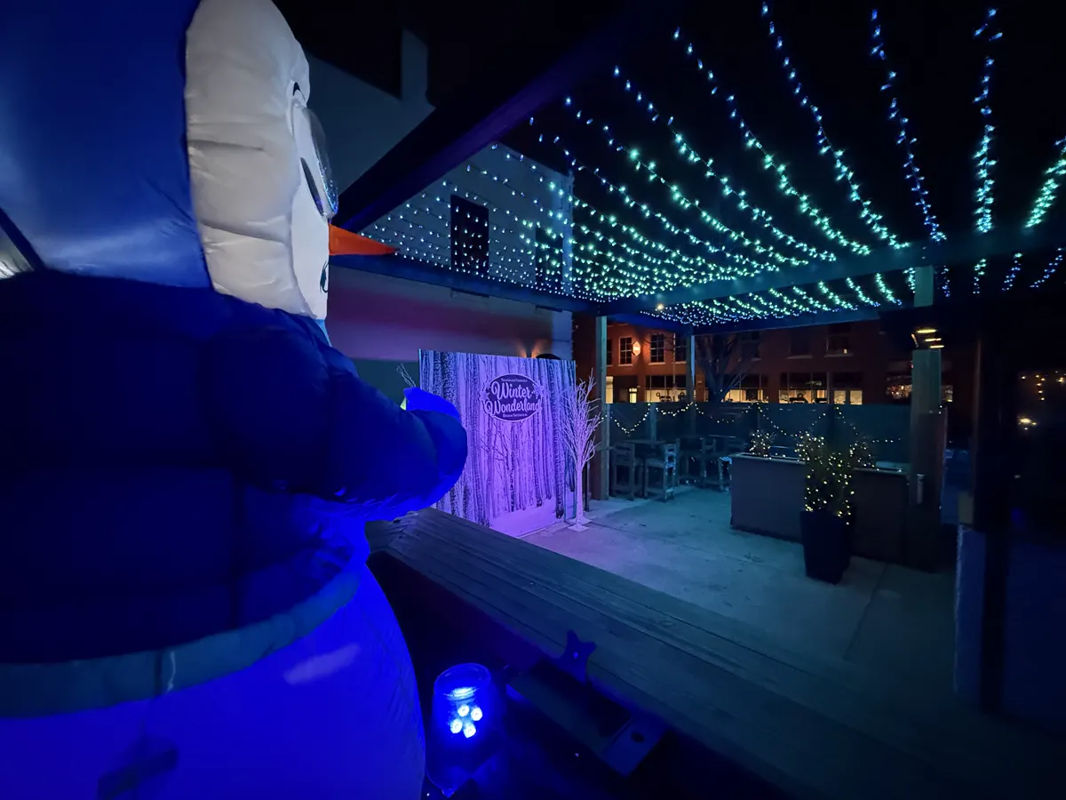 An inflatable snowman beside the illuminated Winter Wonderland patio and photo backdrop